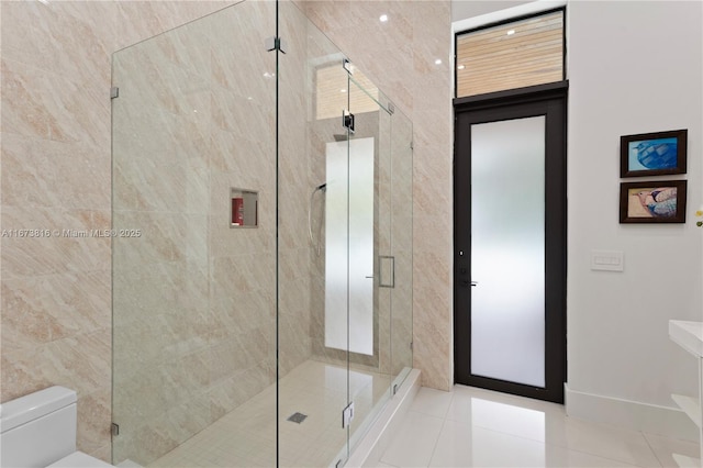 bathroom featuring tile patterned flooring, a shower with shower door, and toilet