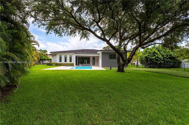 rear view of property with a fenced in pool, a patio area, and a lawn