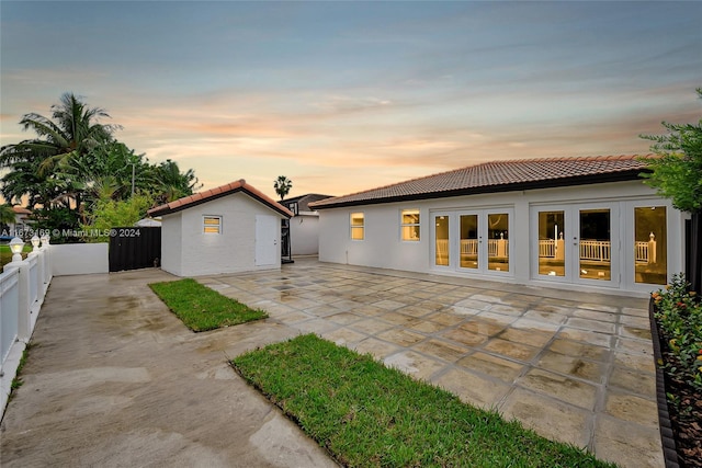 back house at dusk featuring a patio area