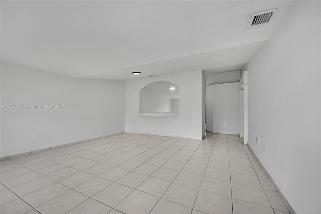 tiled empty room featuring a textured ceiling