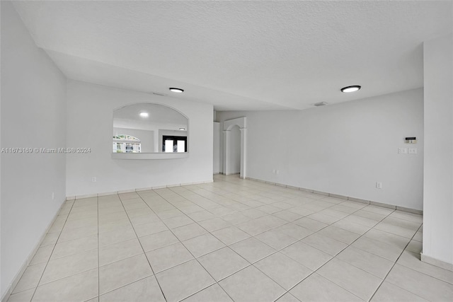 tiled empty room featuring a textured ceiling