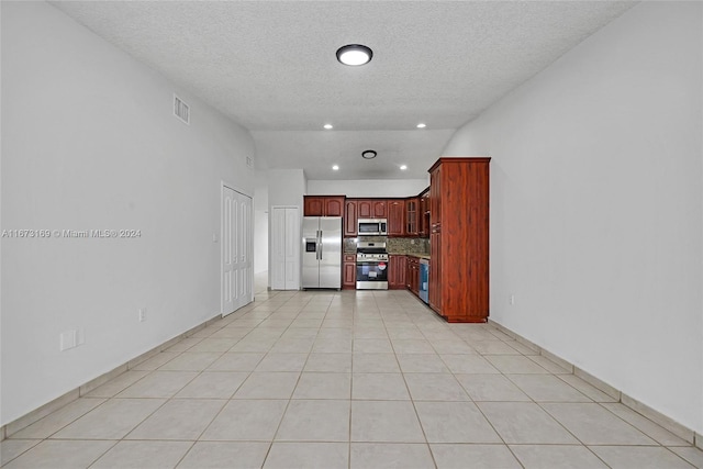 kitchen featuring appliances with stainless steel finishes, a textured ceiling, tasteful backsplash, and light tile patterned flooring