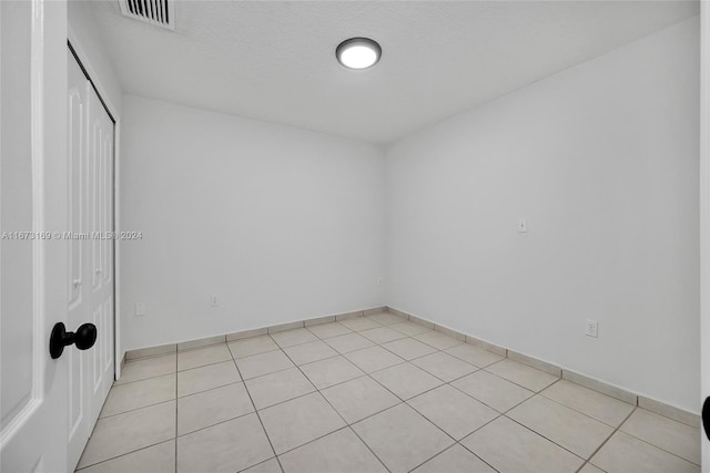 tiled empty room featuring a textured ceiling