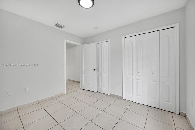 unfurnished bedroom featuring light tile patterned floors and two closets