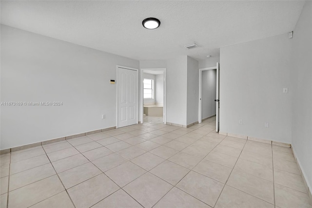 tiled empty room with a textured ceiling