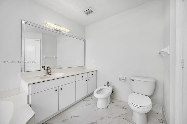 bathroom with a tub to relax in, a textured ceiling, toilet, vanity, and a bidet