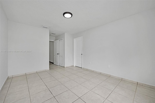 unfurnished room with a textured ceiling and light tile patterned floors