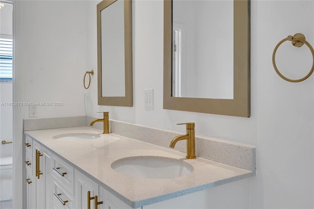 full bathroom featuring a sink, toilet, and double vanity