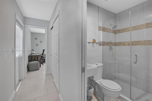 bathroom featuring baseboards, a shower stall, toilet, and tile patterned floors