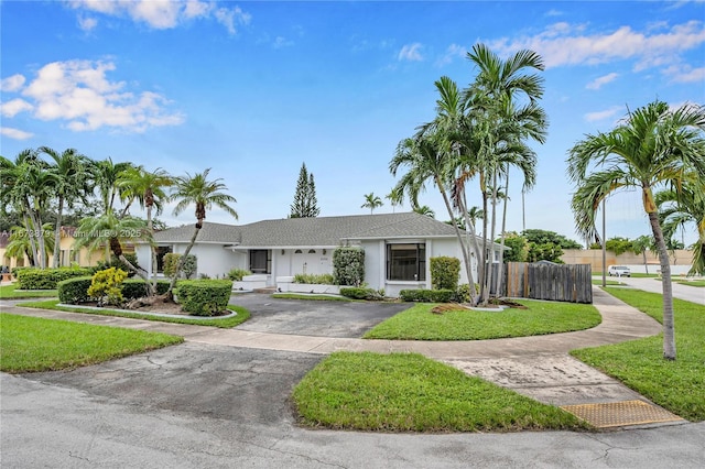 view of front of home featuring aphalt driveway, a front lawn, fence, and stucco siding