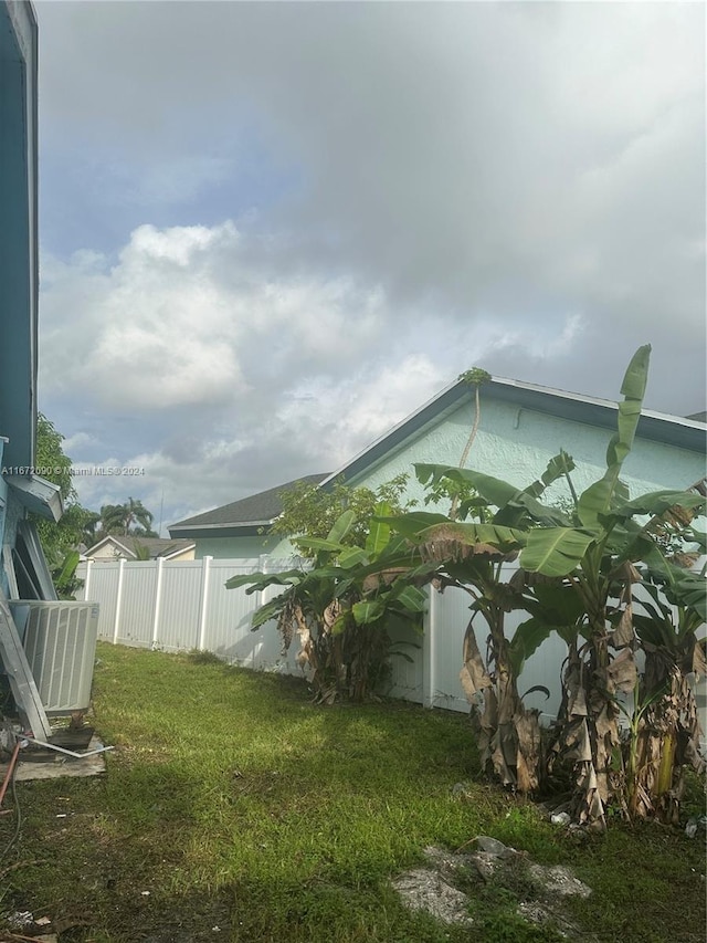 view of side of home with central air condition unit and a lawn