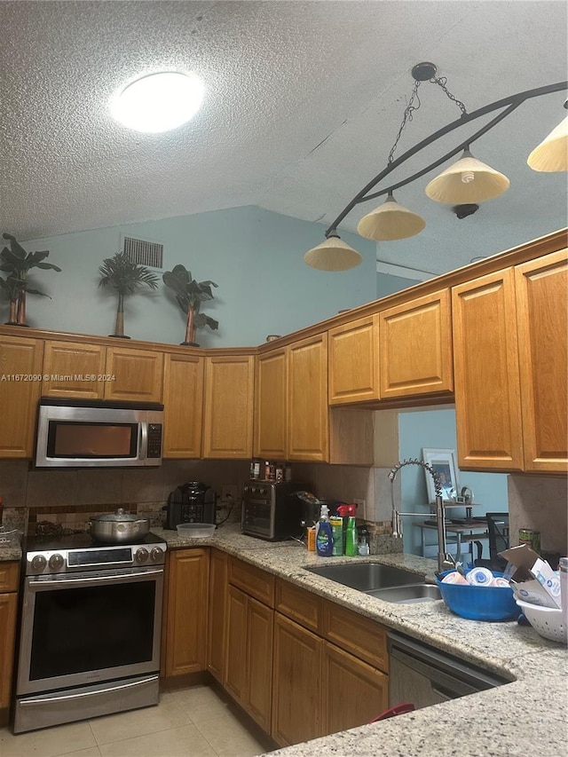 kitchen with light tile patterned floors, sink, a textured ceiling, stainless steel appliances, and vaulted ceiling