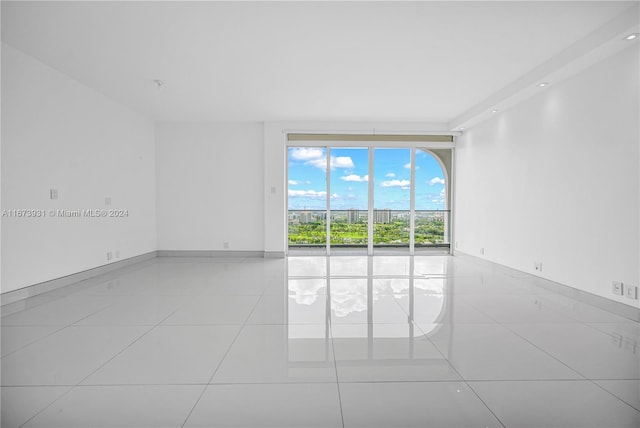 empty room with expansive windows and light tile patterned floors