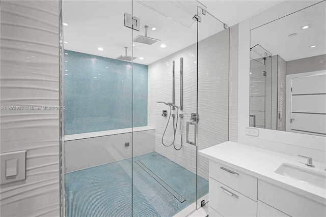 bathroom featuring a shower with shower door, vanity, and tile walls