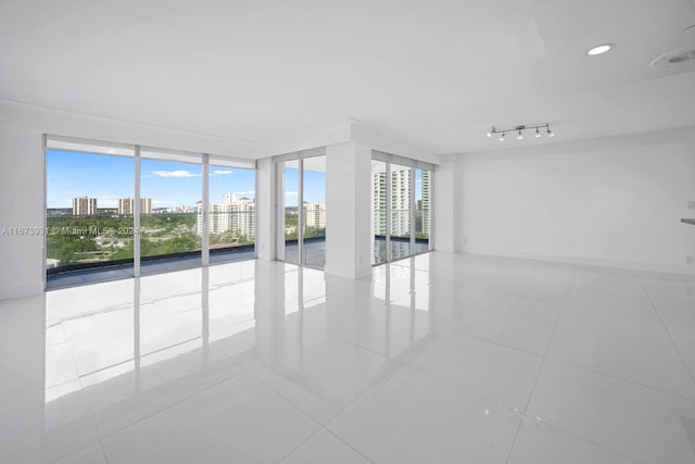 spare room with expansive windows and light tile patterned floors