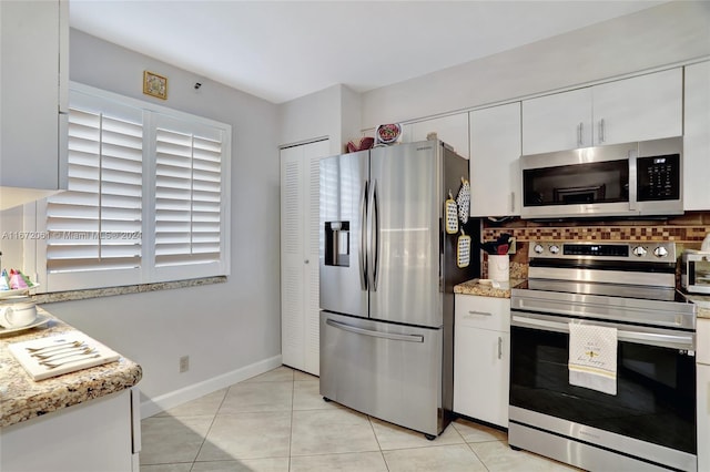 kitchen with decorative backsplash, stainless steel appliances, light stone countertops, white cabinets, and light tile patterned floors