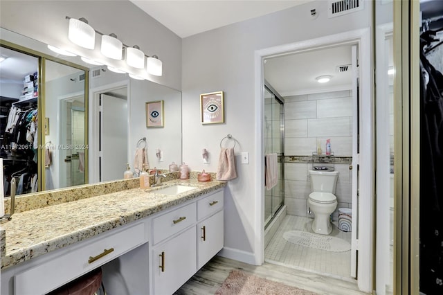 bathroom with a shower with door, hardwood / wood-style floors, vanity, and toilet