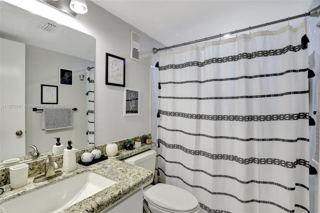 bathroom with curtained shower, vanity, and toilet