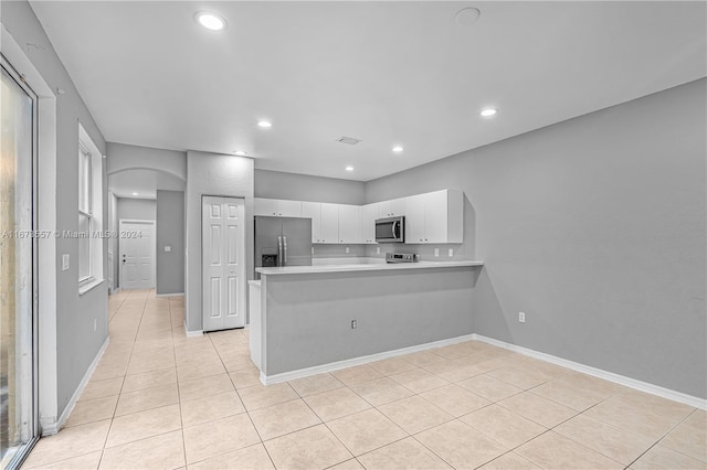 kitchen featuring appliances with stainless steel finishes, kitchen peninsula, white cabinetry, and light tile patterned floors