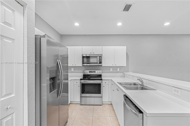 kitchen with appliances with stainless steel finishes, sink, light tile patterned floors, and white cabinets