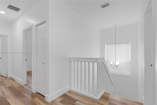 hallway featuring a chandelier and light hardwood / wood-style flooring