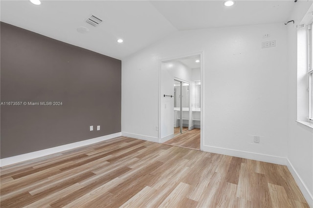 unfurnished room featuring light wood-type flooring and vaulted ceiling