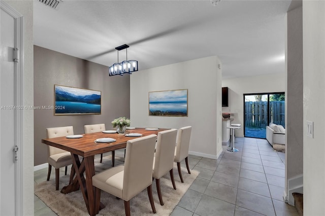 tiled dining room with an inviting chandelier