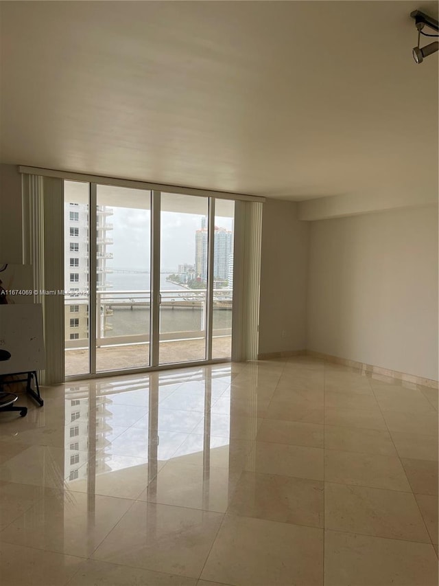 tiled empty room featuring floor to ceiling windows and plenty of natural light