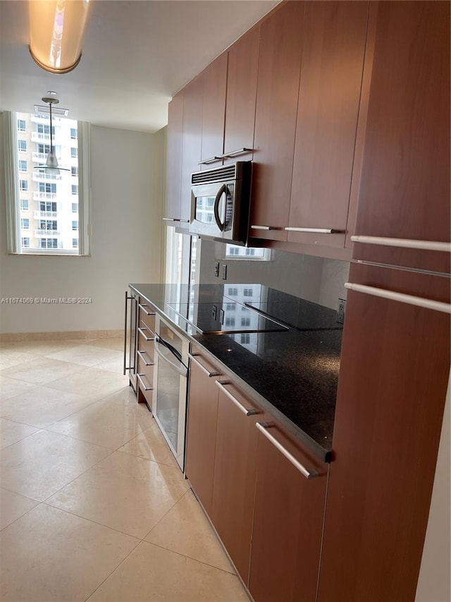 kitchen featuring appliances with stainless steel finishes, decorative light fixtures, and light tile patterned flooring