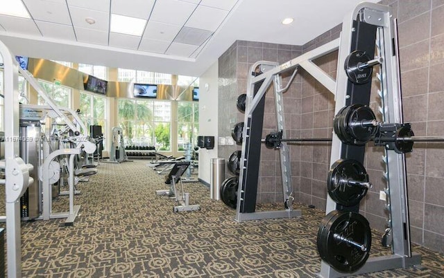 exercise room featuring carpet floors and tile walls