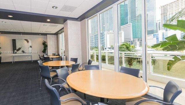 carpeted dining space with a paneled ceiling and plenty of natural light