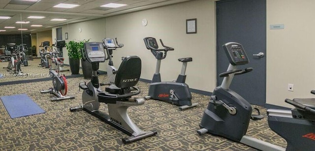 workout area with dark colored carpet and a paneled ceiling