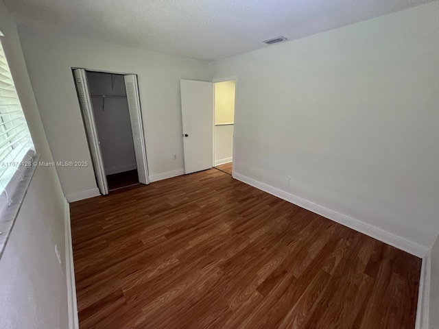 unfurnished bedroom featuring a closet and dark hardwood / wood-style flooring