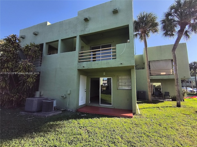 back of house with a balcony, a yard, and central AC