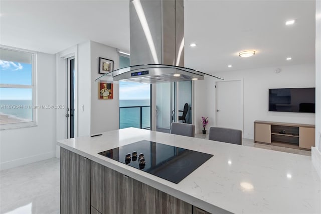 kitchen featuring black electric cooktop, island range hood, and light stone countertops