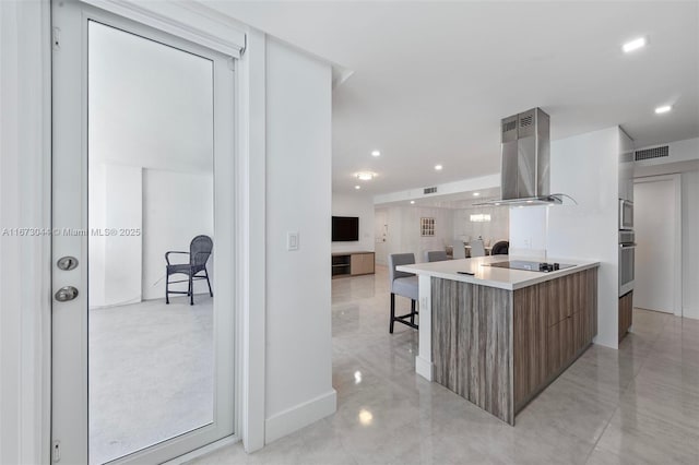 kitchen featuring a breakfast bar area, black electric cooktop, stainless steel oven, and range hood