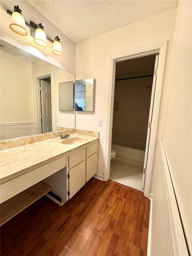 bathroom featuring hardwood / wood-style flooring, vanity, toilet, and a textured ceiling