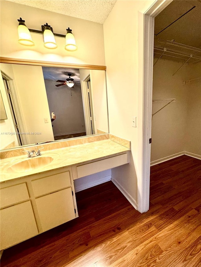 bathroom with ceiling fan, vanity, hardwood / wood-style floors, and a textured ceiling