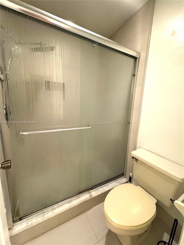 bathroom featuring walk in shower, toilet, and tile patterned floors