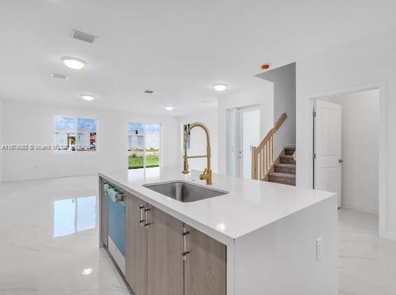 kitchen featuring a center island with sink, sink, and stainless steel dishwasher