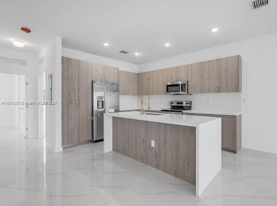 kitchen featuring appliances with stainless steel finishes, sink, and a center island with sink