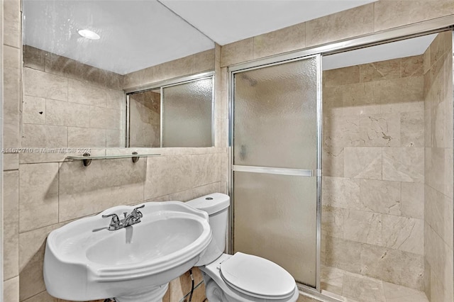 bathroom featuring walk in shower, sink, toilet, and tile walls