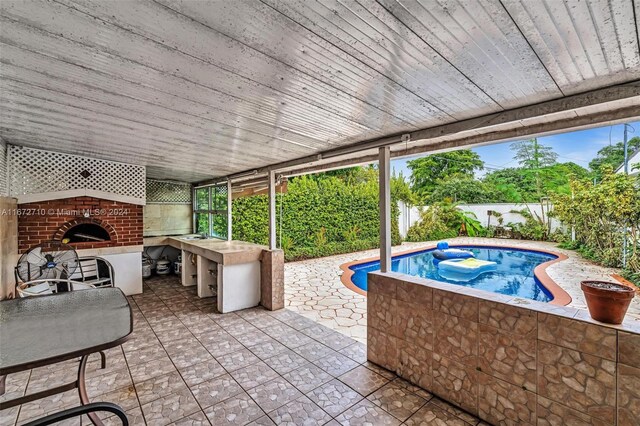 view of patio / terrace featuring a fireplace and a swimming pool with hot tub