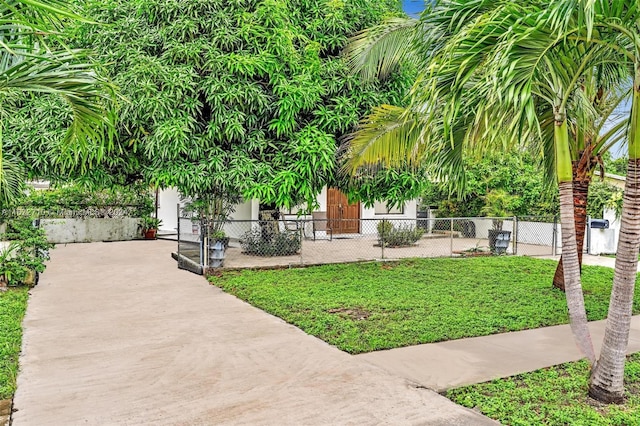 view of property's community with fence, a lawn, and concrete driveway