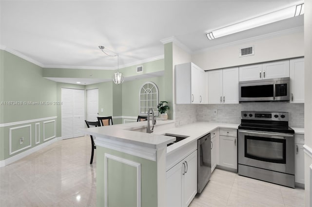 kitchen featuring kitchen peninsula, stainless steel appliances, crown molding, sink, and decorative light fixtures