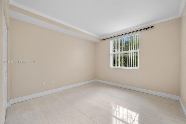 empty room with crown molding and light tile patterned flooring