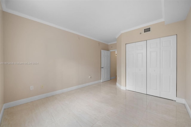 unfurnished bedroom with crown molding and a closet