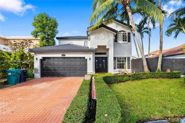 traditional-style house with a front yard, a garage, fence, stucco siding, and decorative driveway