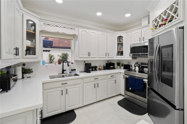 kitchen with white cabinetry, appliances with stainless steel finishes, a sink, and ornamental molding