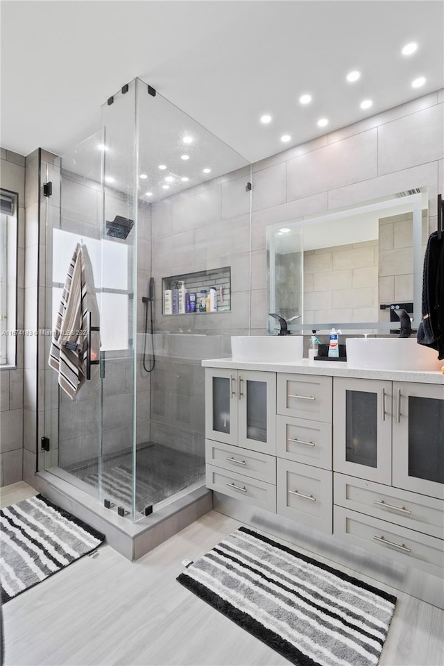 full bathroom with tile walls, a stall shower, vanity, and recessed lighting
